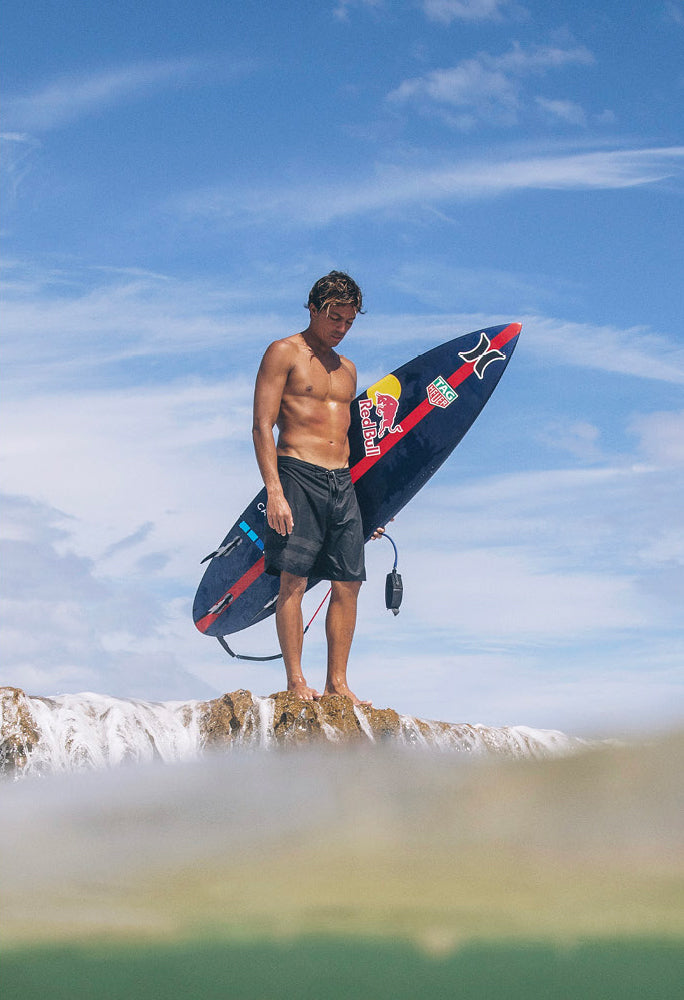 Surfer mit Board auf den Felsen